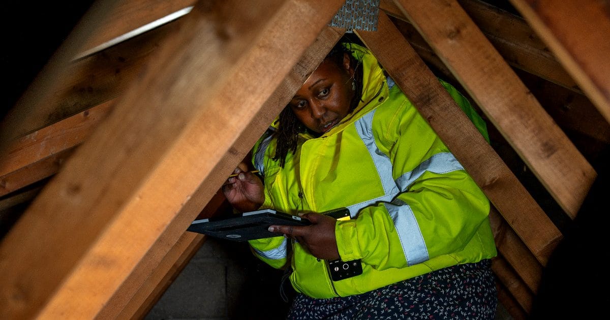 Structural engineer inspecting roof trusses inside a loft space during a loft conversion feasibility survey