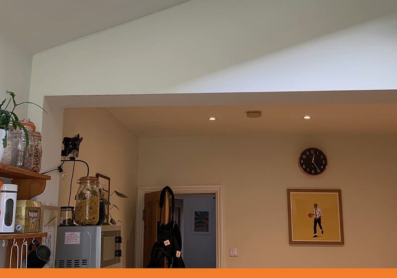 Open-plan kitchen extension with a vaulted ceiling and rooflight, opening through a boxed-in steel beam into the dining room after a load-bearing wall was removed