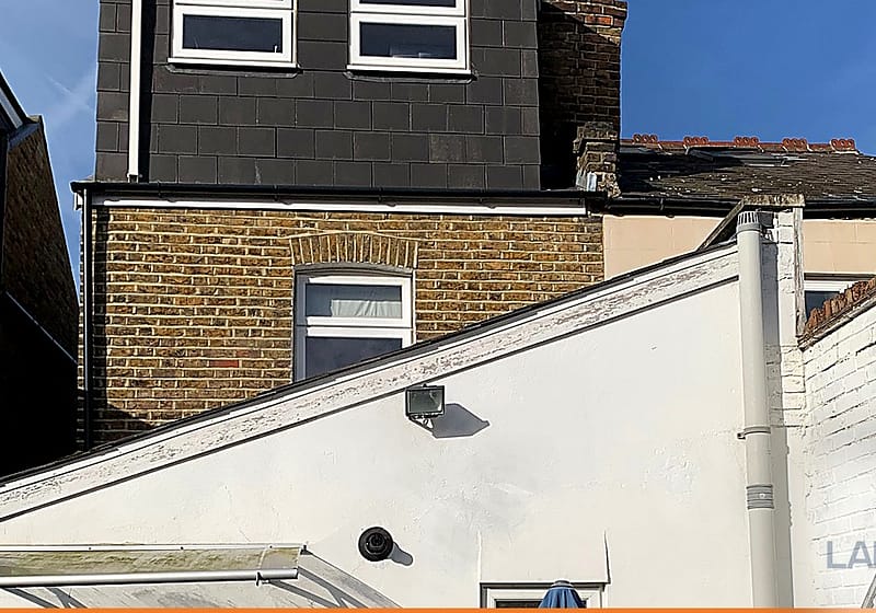 White rendered extension meeting the brickwork of the original house at roof level